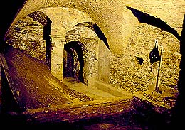 Sklepení domu v průběhu výzkumu. V pozadí vidíme původní arkády, pozůstatek nejstarší kamenné fáze stavby (fáze B). Arkády byly ve středověku otevřeny do dvora v zadní části parcely domu. Foto Michal Ernée. 